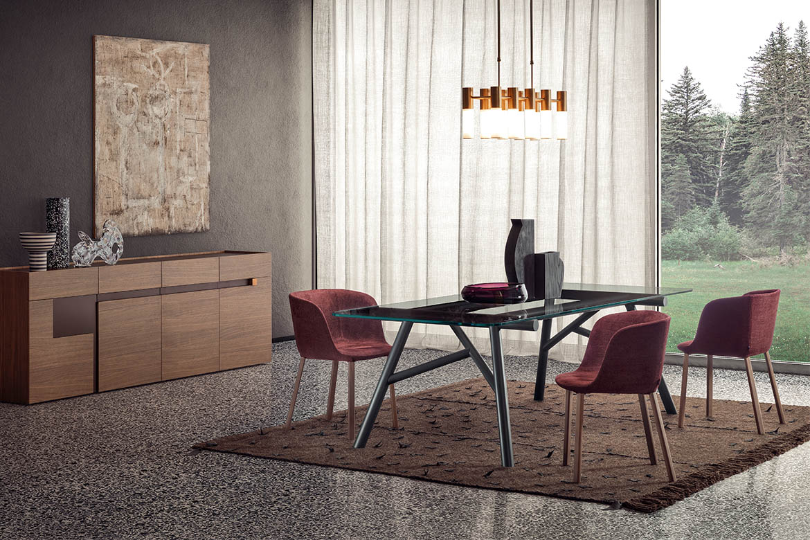 tavolo maestro con struttura in legno grigio con piano in vetro trasparente, sedie esse con braccioli , credenza in legno con pomolo in metallo, tappeto in legno con inserti in pelle tessoria asolana