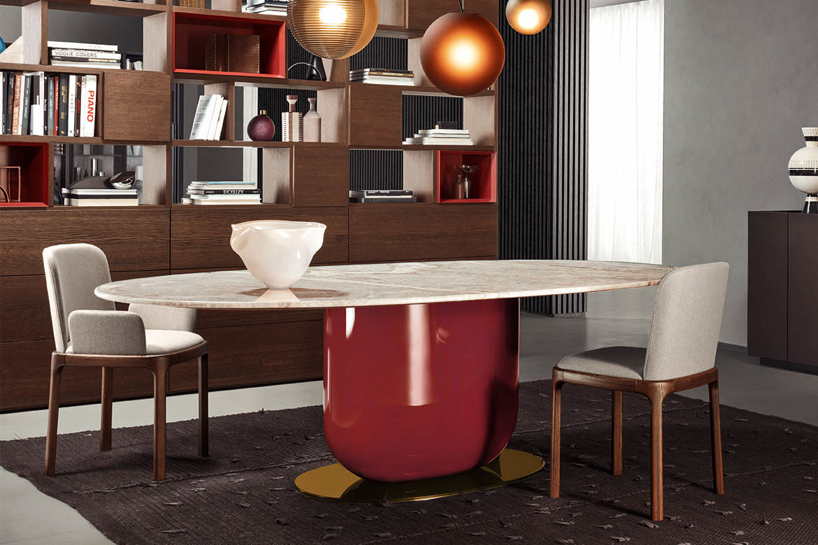 tavolo ettore con piano elittico in marmo fior di pesco, base con colonna centrale rossa e piatto in bronzo, tappeto teseo con inserti in pelle tessoria asolana, libreria bifacciale con moduli a giorno spazioteca pianca