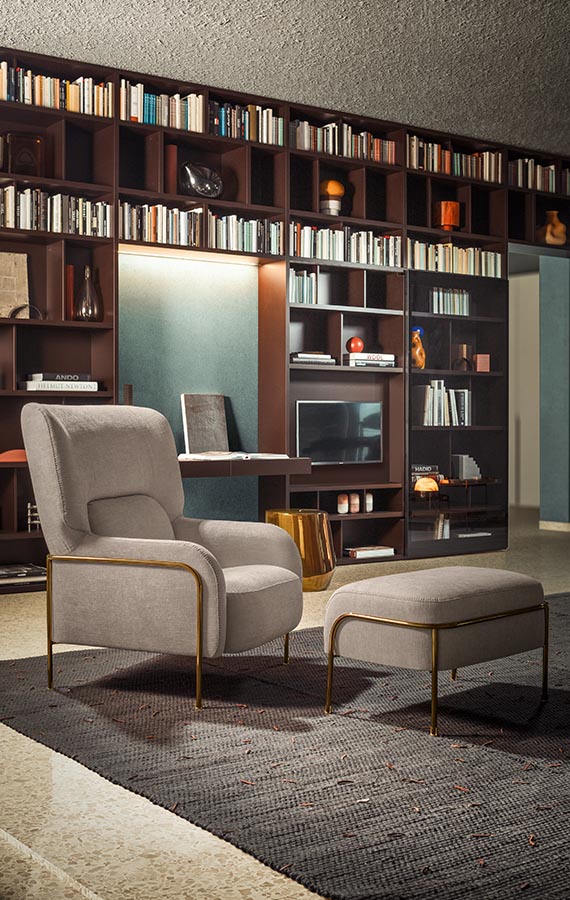 poltrona platea con rivestimento in tessuto grigio e struttura in tubolare color bronzo, in retroscena libreria Spazioteca con scrittoio Ala e ante in vetro scorrevoli pianca
