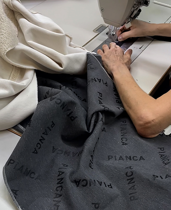 Mani al lavoro nella produzione Pianca, cucitura artigianale di tessuti per arredi di design Made in Italy