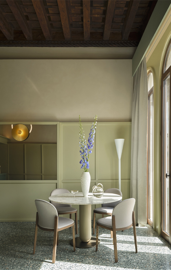 Zona pranzo di Elizabeth Unique Venice con tavolo rotondo, sedie imbottite, boiserie e travi storiche in legno a vista
