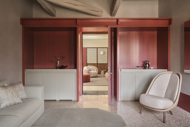 Suite di Elizabeth Unique Venice con arredi Pianca su misura, boiserie rosso veneziano, divano chiaro e poltrona Calatea imbottita